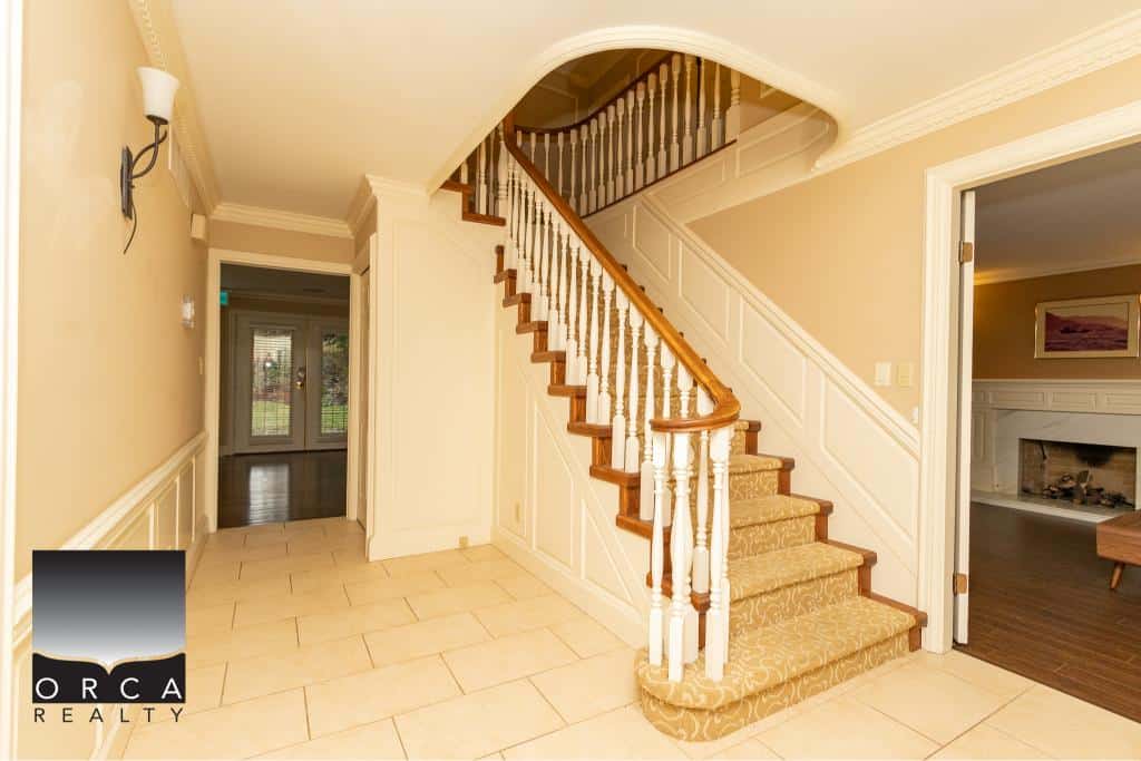 Spacious interior of a luxury home with elegant staircase and classic decor, showcasing Orca Realty Inc. expert real estate services for Vancouver Island and surrounding areas.