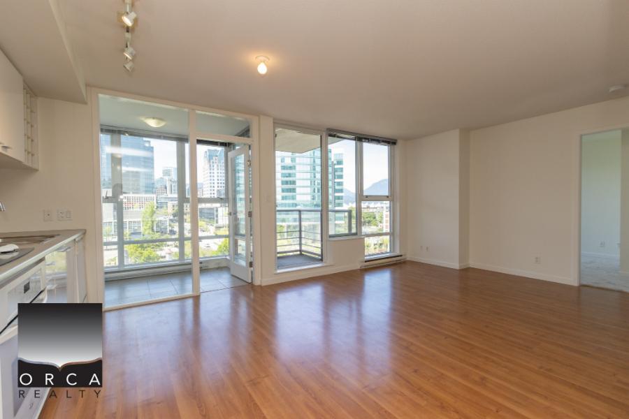 Spacious modern apartment living room with large windows, city views, hardwood flooring, and balcony access, ideal for urban lifestyles and real estate investment in Vancouver.