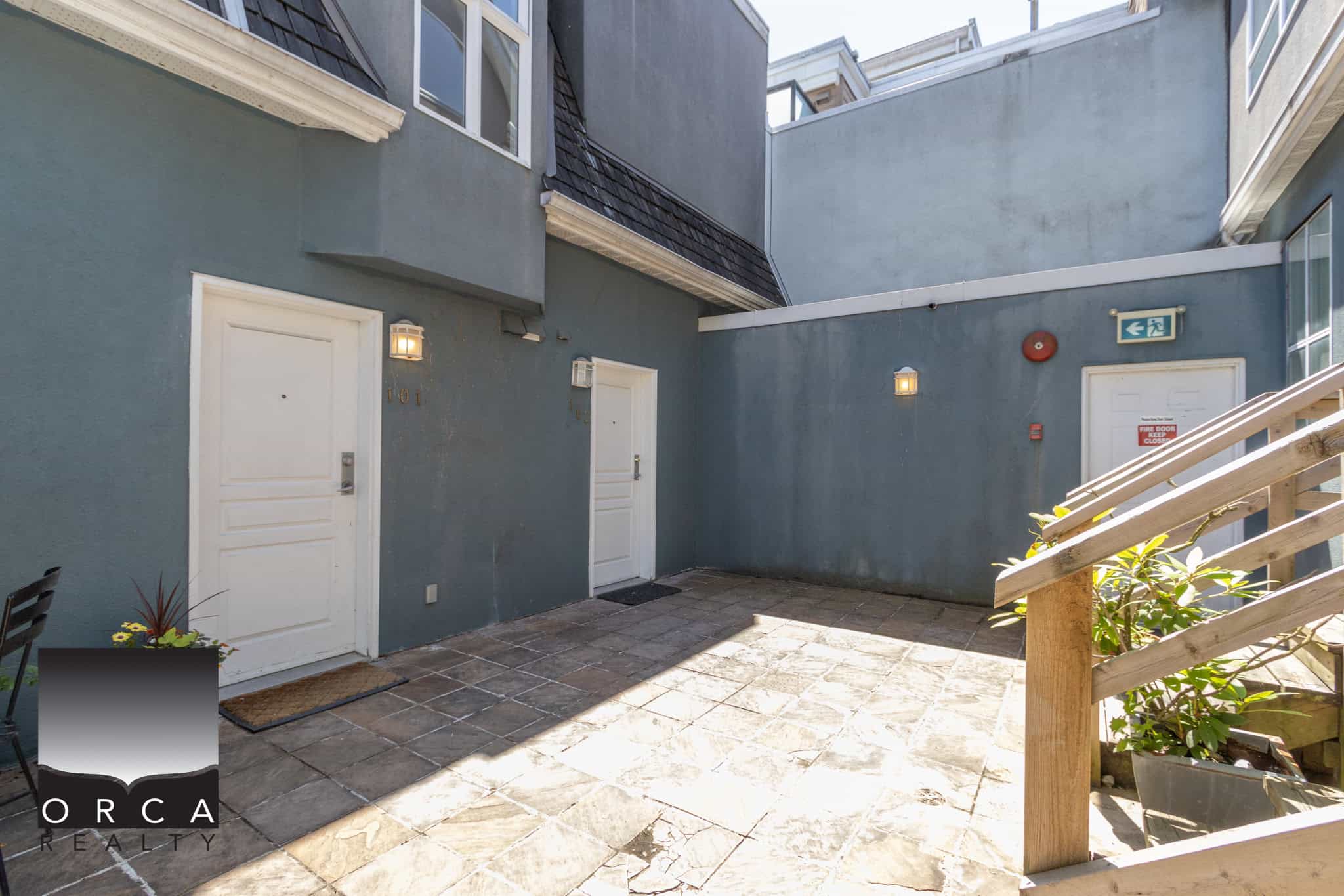 Modern townhouse courtyard with patio flooring, white exterior doors, and surrounding blue-grey walls, ideal for residential property listings in Vancouver.
