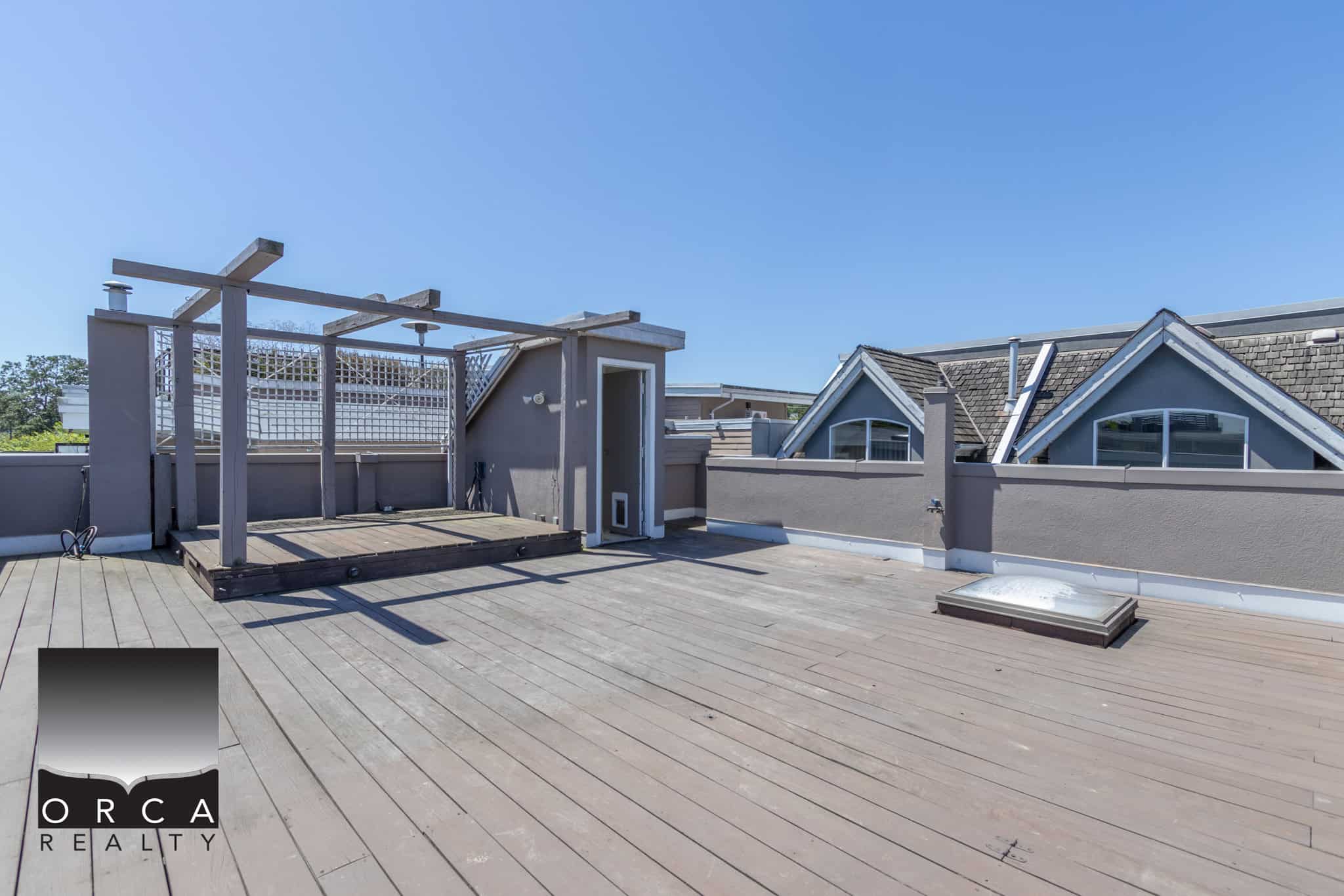 Spacious rooftop deck with wooden flooring, rooftop access, and city views, perfect for outdoor entertaining and relaxation in Vancouver, BC.