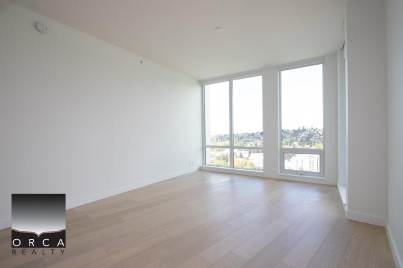 Bright modern living room with large windows offering panoramic city views, featuring hardwood flooring and neutral walls, ideal for Vancouver real estate buyers.