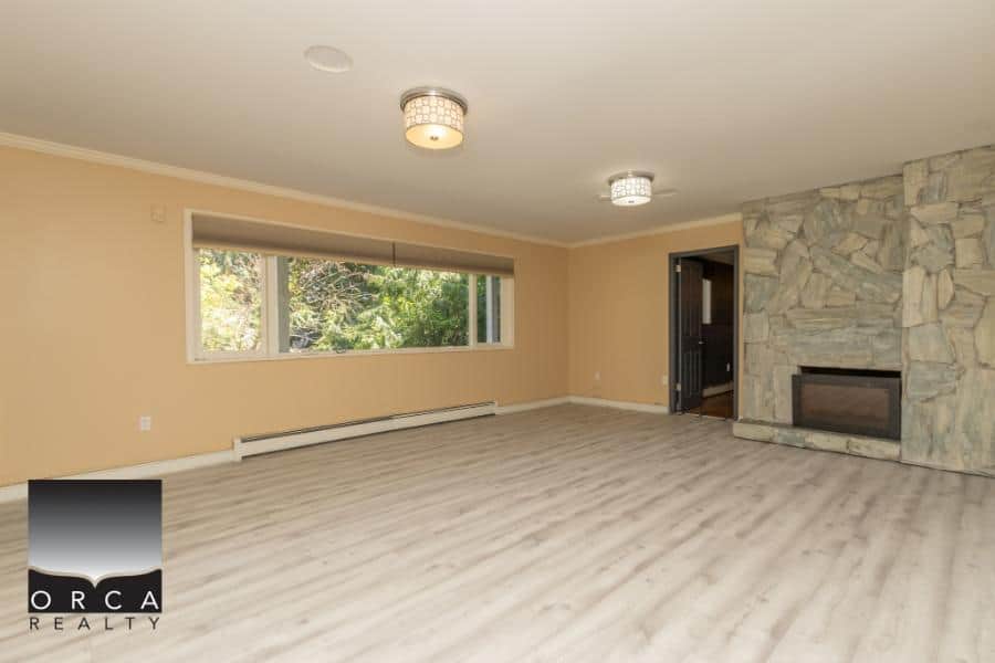 Spacious living room with large window, modern fireplace, and neutral decor in a beautiful Vancouver home. Ideal for family relaxation and entertaining guests.