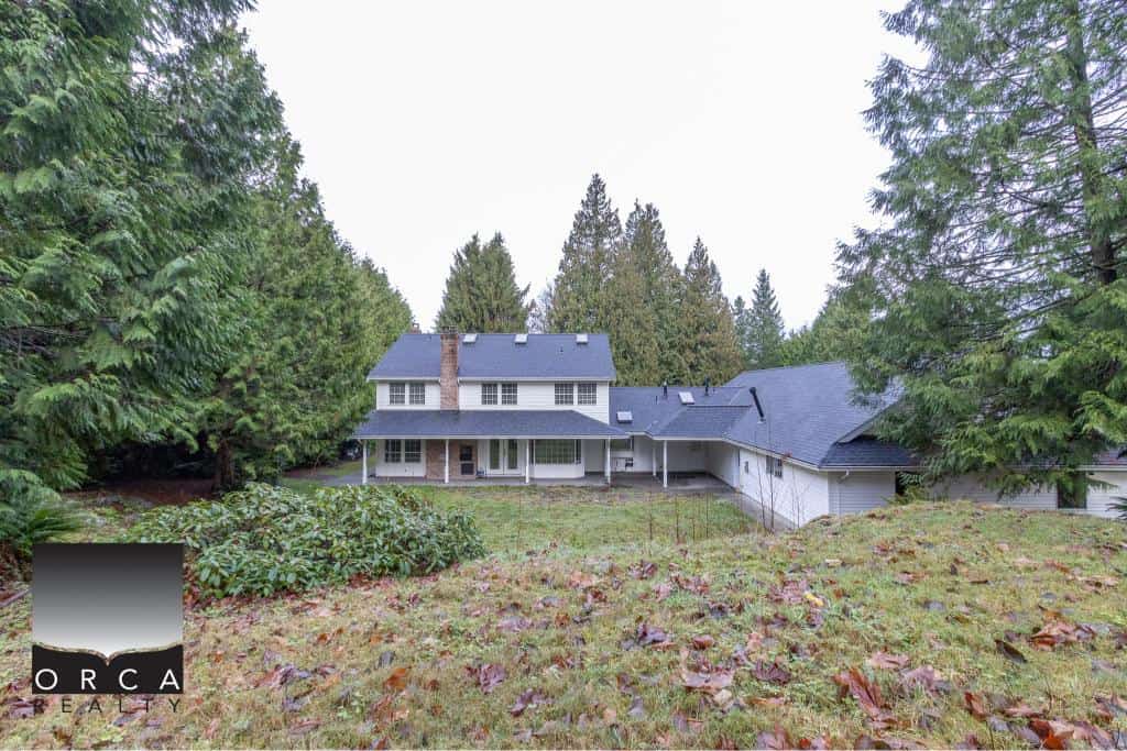 Spacious family home surrounded by lush greenery and tall trees in a tranquil, wooded setting in Vancouver Island, ideal for real estate investment and outdoor living.