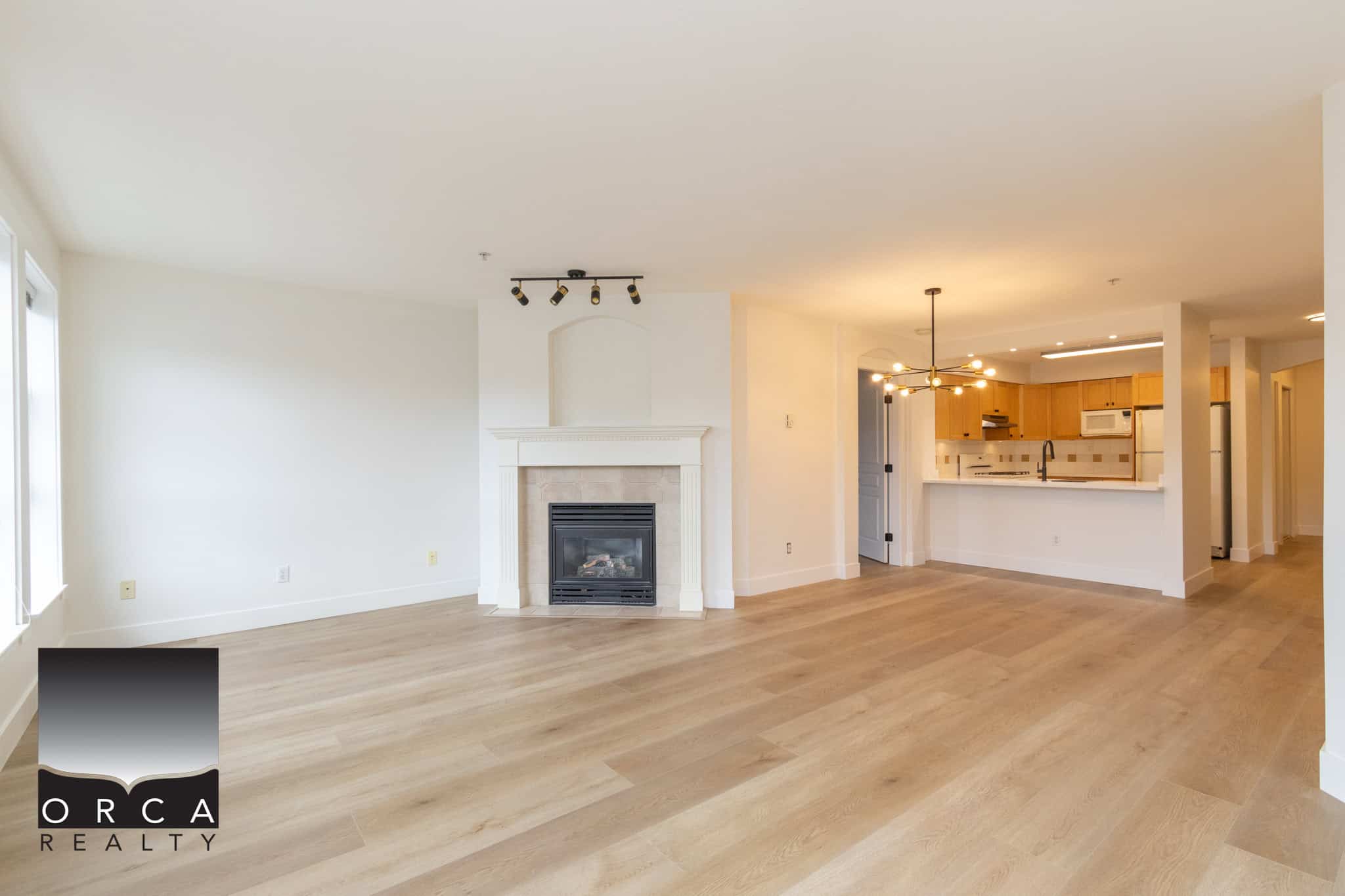 Spacious open-concept living room with modern fireplace, light hardwood floors, and bright natural lighting, ideal for Vancouver Island real estate buyers.