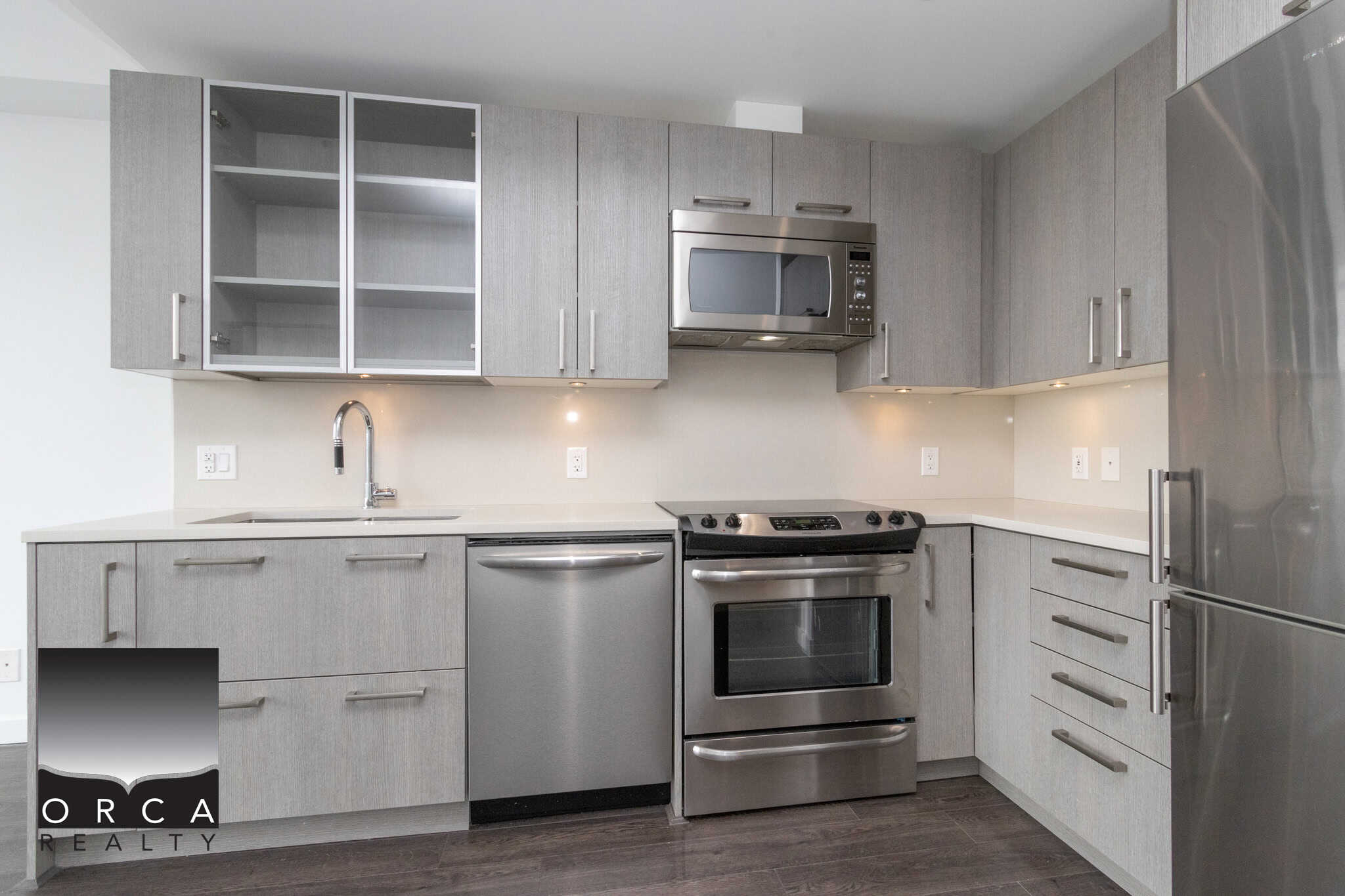 Contemporary grey kitchen with stainless steel appliances, including a microwave, oven, and refrigerator, ideal for modern living and real estate listings in Vancouver.
