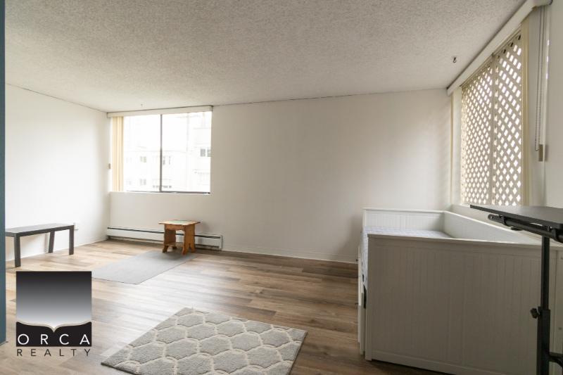 Bright empty apartment living room with large windows and hardwood flooring, perfect for real estate listing in Vancouver.