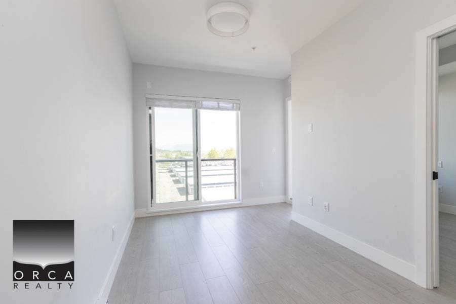 Bright modern rental apartment with large balcony and scenic views, featuring sleek white interior, laminate flooring, and ample natural light, ideal for urban living in the Vancouver area.