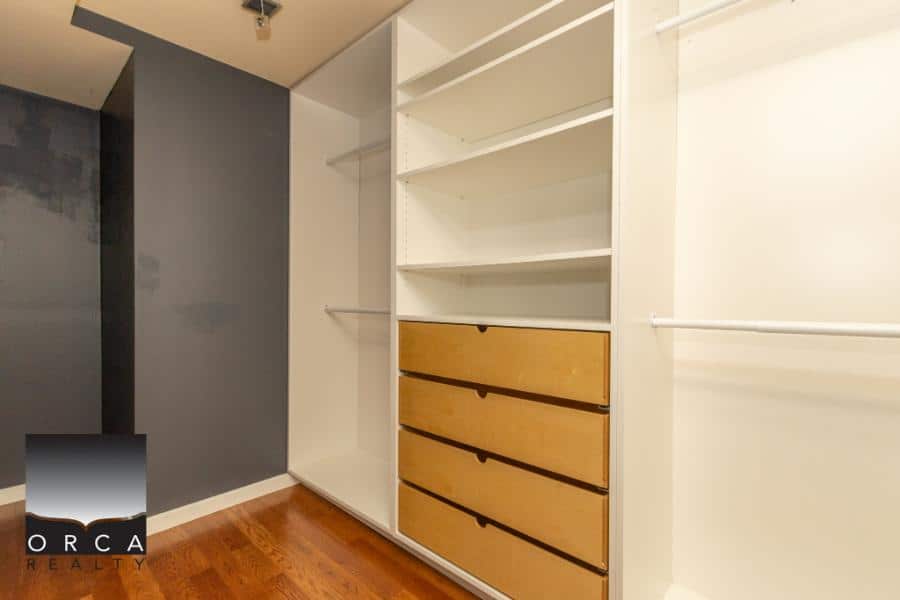 Bright walk-in closet with custom white shelving, open drawers, and hanging rods, ideal for organized storage in Vancouver homes.