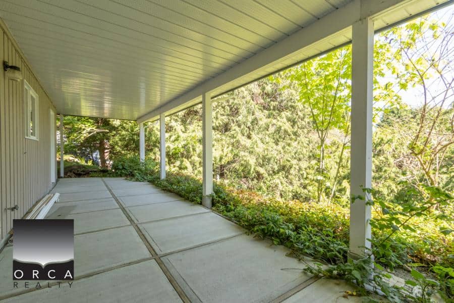 Spacious covered outdoor patio with scenic forest views and lush greenery, ideal for relaxing or entertaining in Kelowna homes. Perfect for outdoor living and enjoying nature.