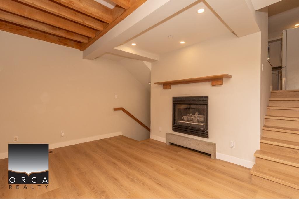 Bright living room featuring a cozy fireplace, modern wood finishes, and stylish staircase with natural light — perfect Vancouver real estate opportunity.