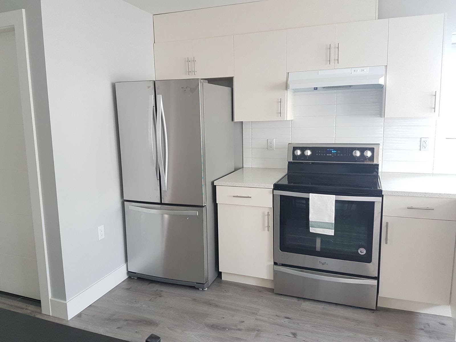 5 Sleek modern kitchen with stainless steel appliances, including a refrigerator and oven, featuring white cabinetry and a clean, minimalist design in a contemporary home.