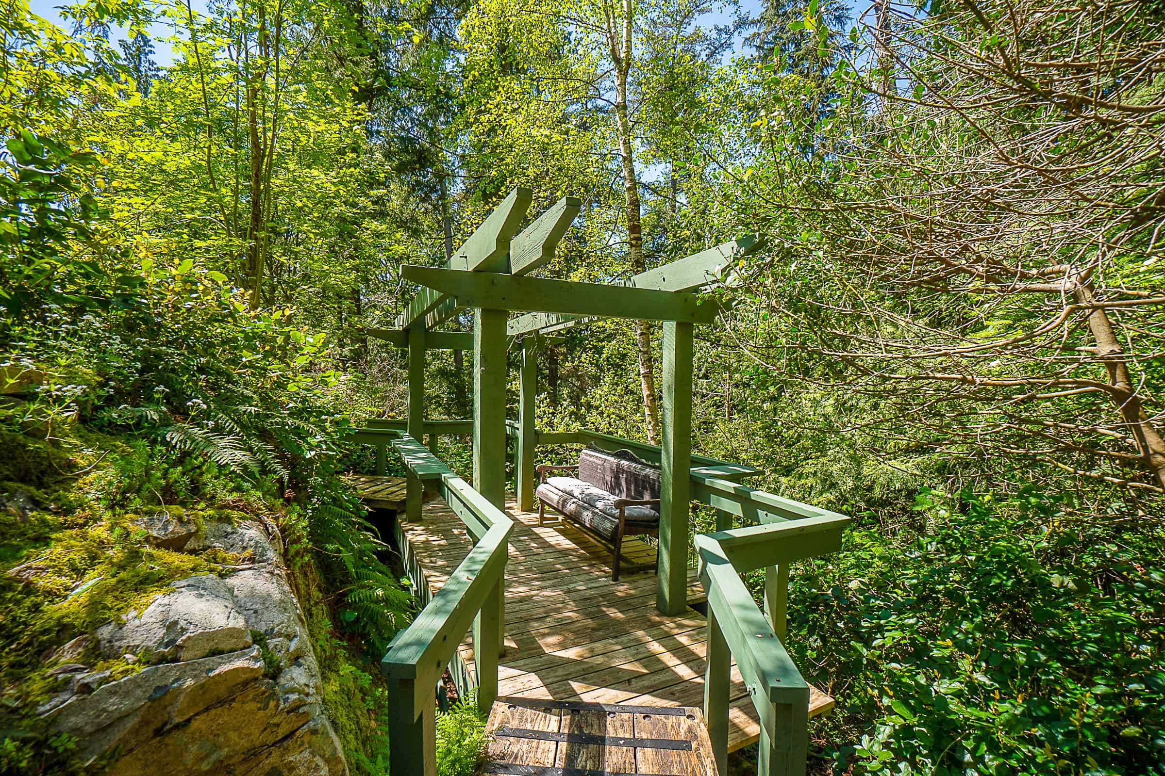Secluded forest viewing deck with seating amidst lush greenery, ideal for outdoor relaxation and nature appreciation in BC.