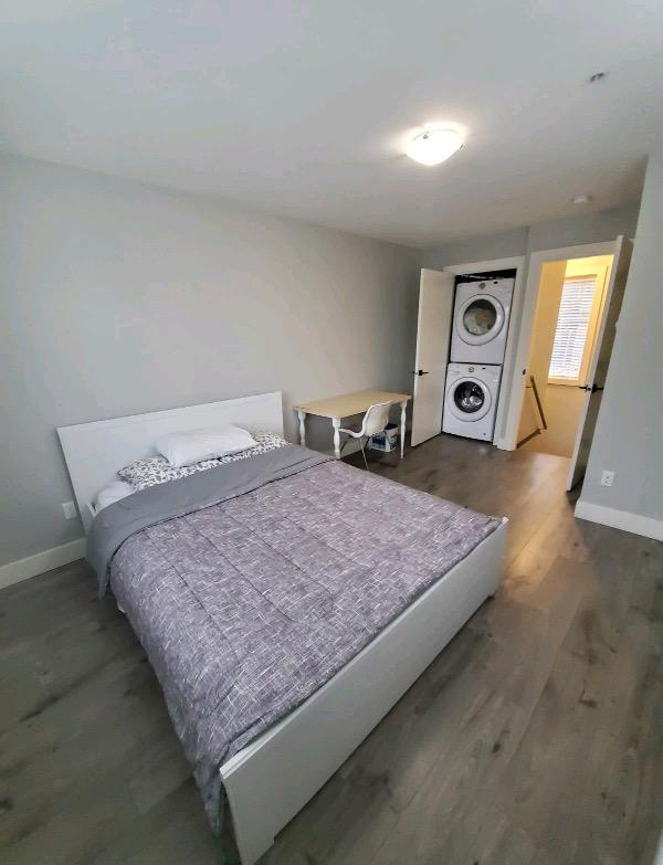 Modern bedroom with gray bedding, white furniture, and hardwood floors in a Vancouver area property listed by Orca Realty Inc.