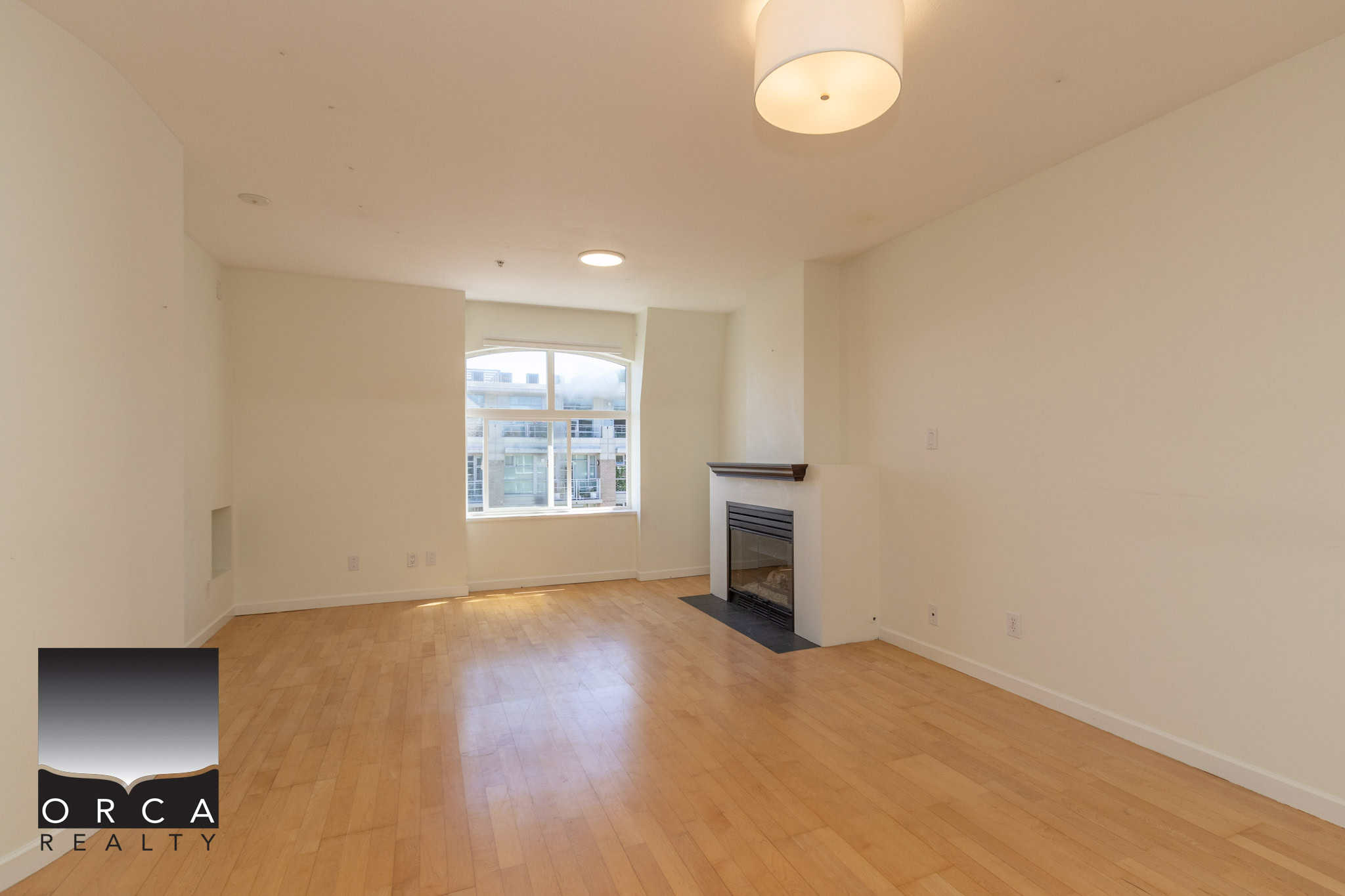 Bright living room with large window, hardwood flooring, and fireplace in modern Vancouver condo. Perfect for family lounging and urban living in the Vancouver real estate market.