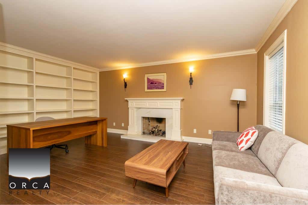 Cozy living room with fireplace, large built-in bookshelves, and modern furniture in a home listed by Orca Realty Inc.