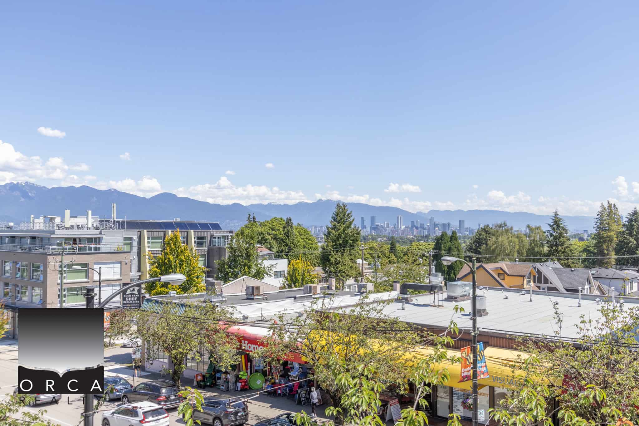 Vibrant cityscape view of Vancouver, featuring a mix of commercial and residential buildings with lush greenery, mountain backdrop, and clear blue sky, highlighting urban living and real estate opportunities in BC.