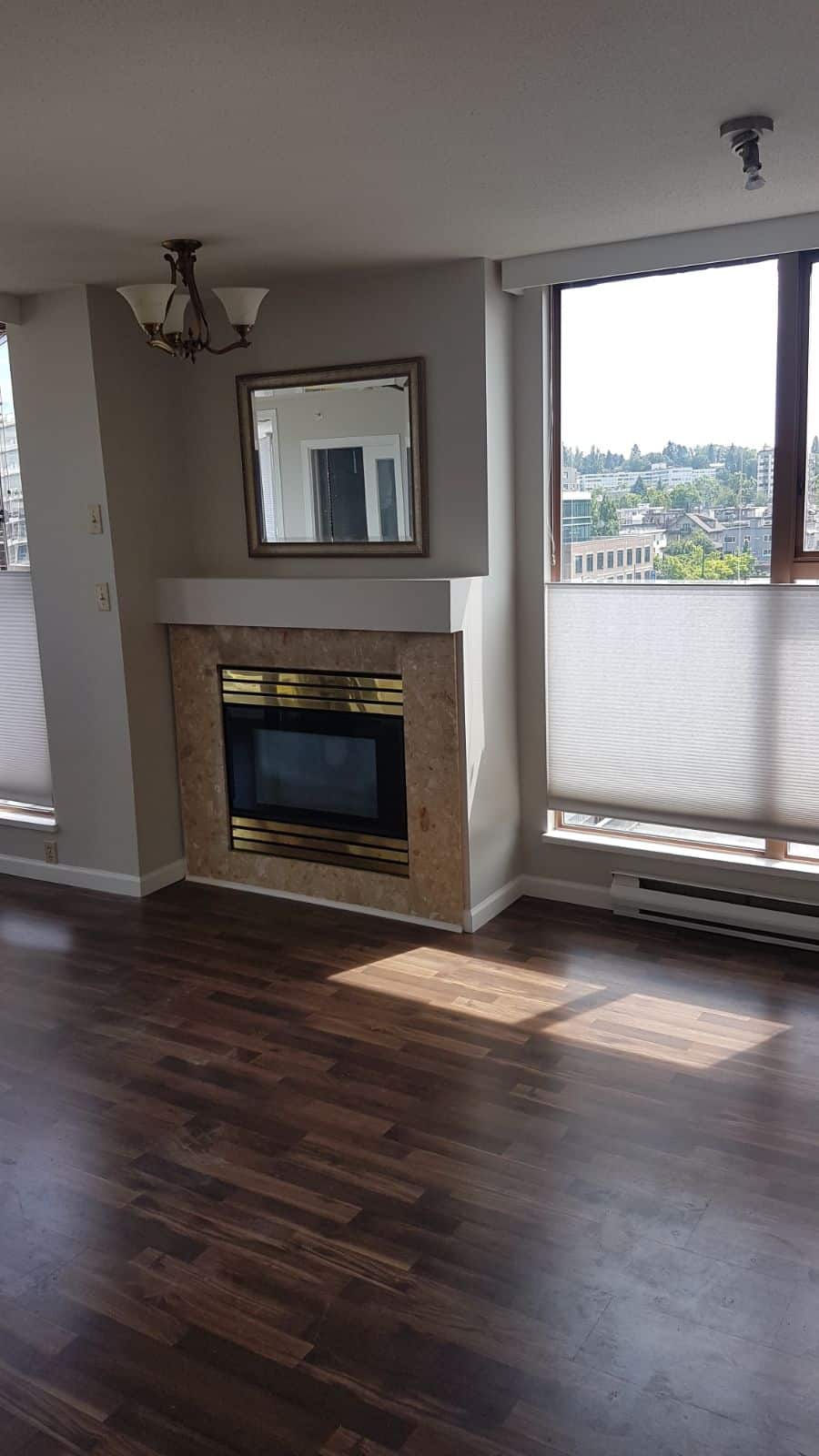 Bright living room with large windows, modern fireplace with marble surround, hardwood floors, and ample natural light, perfect for Vancouver real estate and property investment.