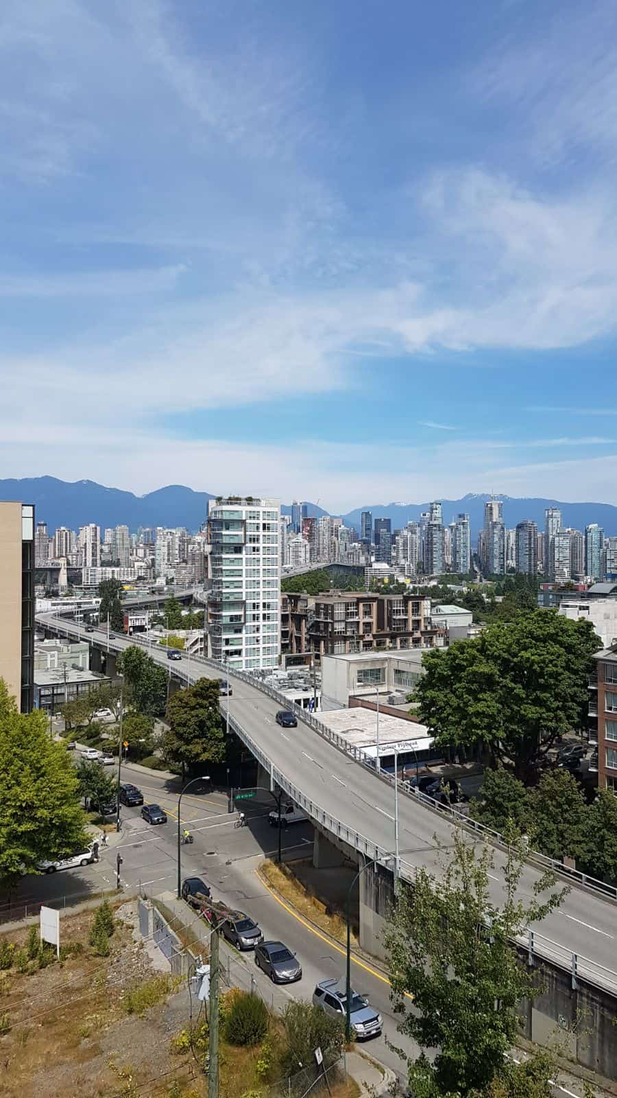 Modern Vancouver skyline with high-rise buildings, urban infrastructure, and scenic mountains in the background, showcasing cityscape view ideal for real estate in Metro Vancouver.
