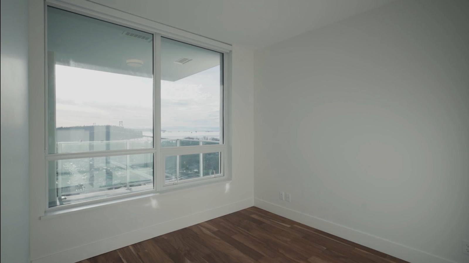 WhatsApp Image 2024-03-02 at 18.27.41 (1) Panoramic city and water view from a modern high-rise condo window in Vancouver, BC, featuring clean white walls and hardwood flooring, perfect for real estate listings by Orca Realty Inc.