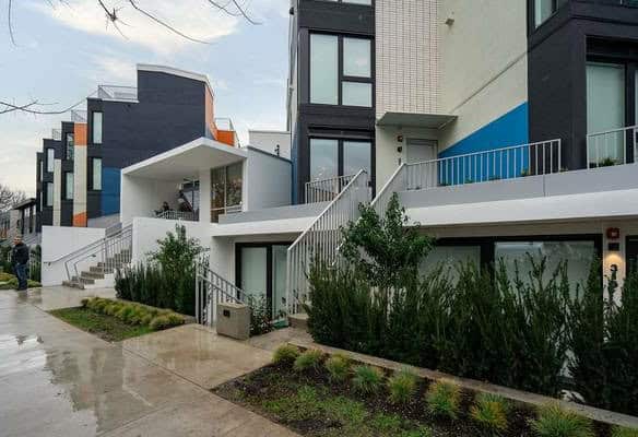 Modern contemporary apartment building with lush landscaped greenery, showcasing luxury residential real estate in Vancouver by Orca Realty Inc.