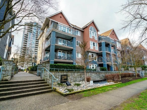 Modern multi-family residential building with balconies, situated in a vibrant urban neighbourhood, featuring landscaped common areas and easy sidewalk access.