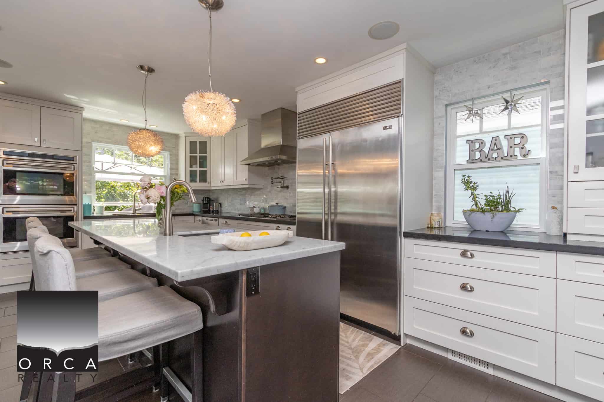 Bright modern kitchen with white cabinets, stainless steel appliances, and elegant pendant lighting, perfect for Vancouver Island homebuyers seeking stylish, functional, and spacious kitchens.