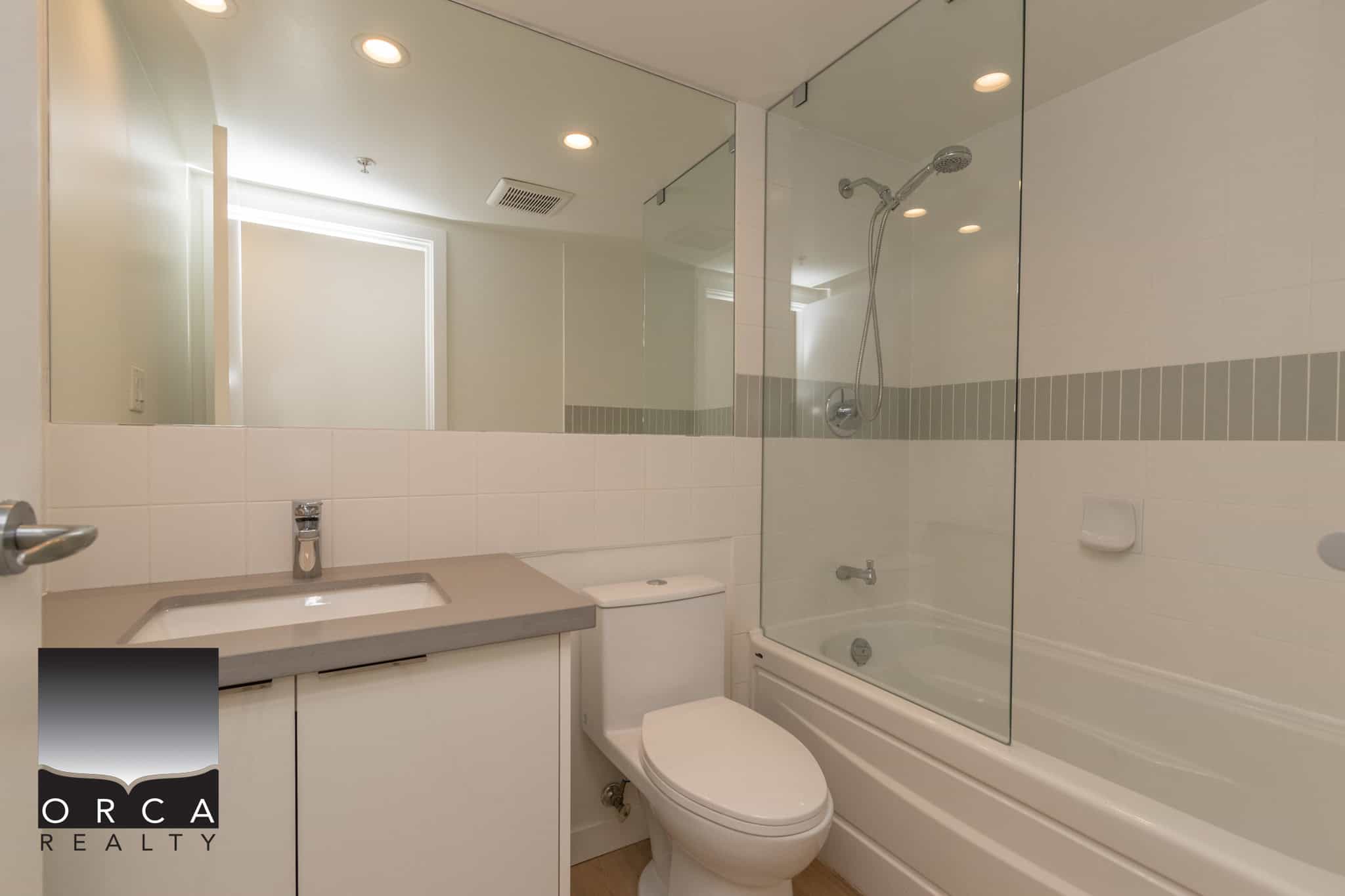11 Modern Vancouver condo bathroom with tub, shower, and sleek fixtures, perfect for comfortable living. Central location and upscale amenities provided by Orca Realty Inc.