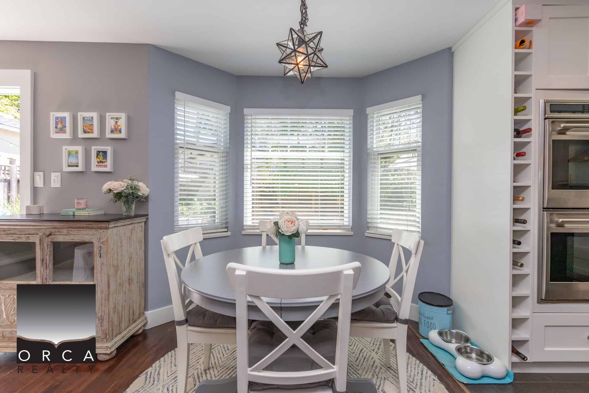 Bright dining area with large bay window, contemporary decor, and a cozy atmosphere in a beautifully maintained home by Orca Realty Inc.