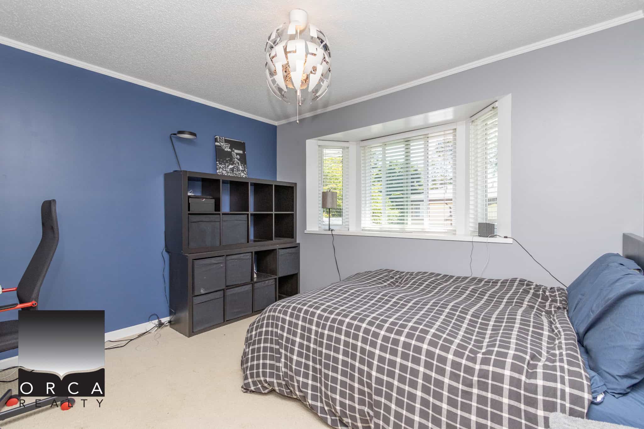 Bright bedroom with a large bay window, modern decor, and a comfortable bed, perfect for relaxing in a Vancouver home listed by Orca Realty Inc.