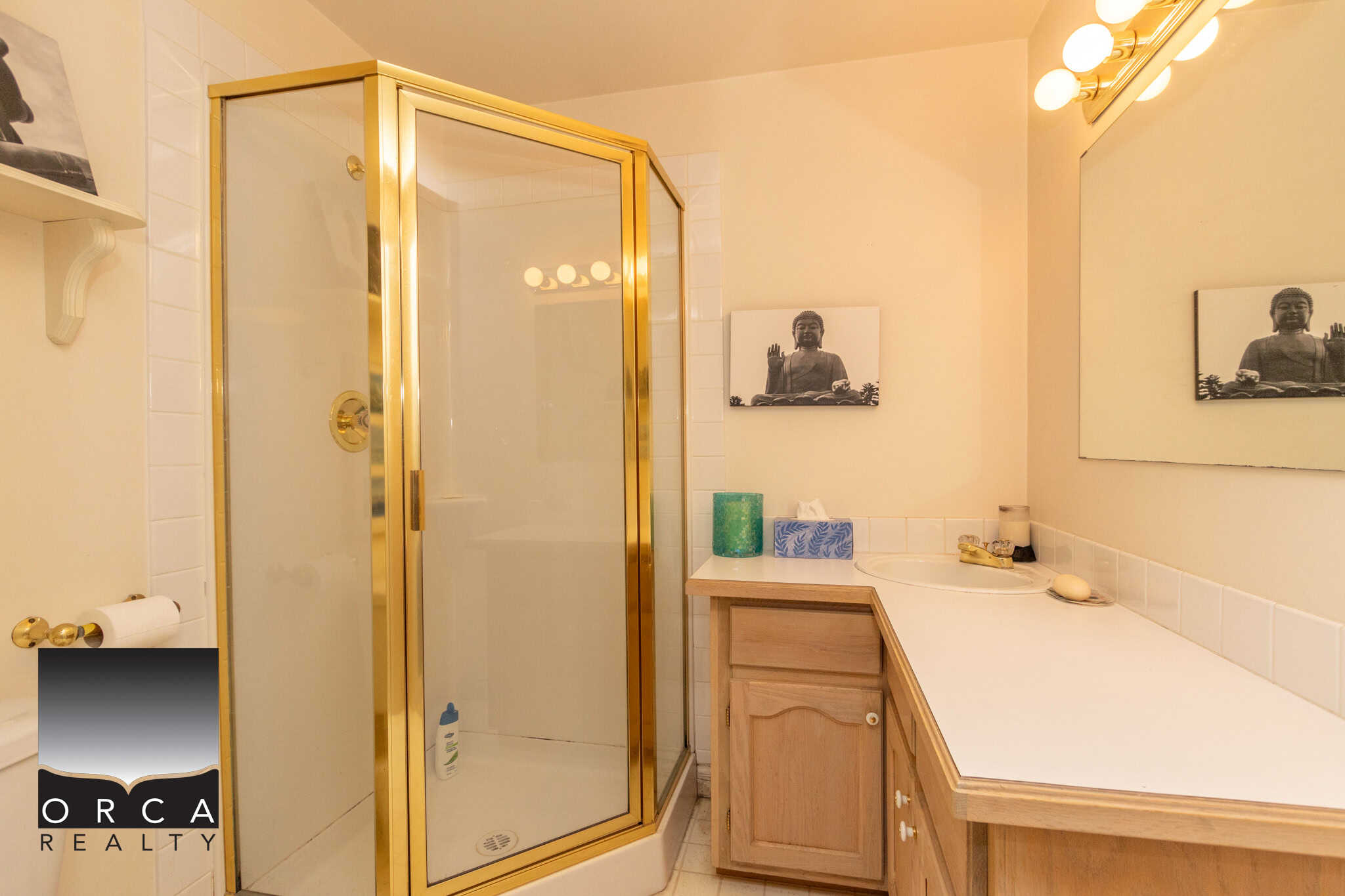 Bright bathroom with a glass shower enclosure, beige cabinets, and decorative Buddha artwork, featuring everyday essentials for a comfortable home.