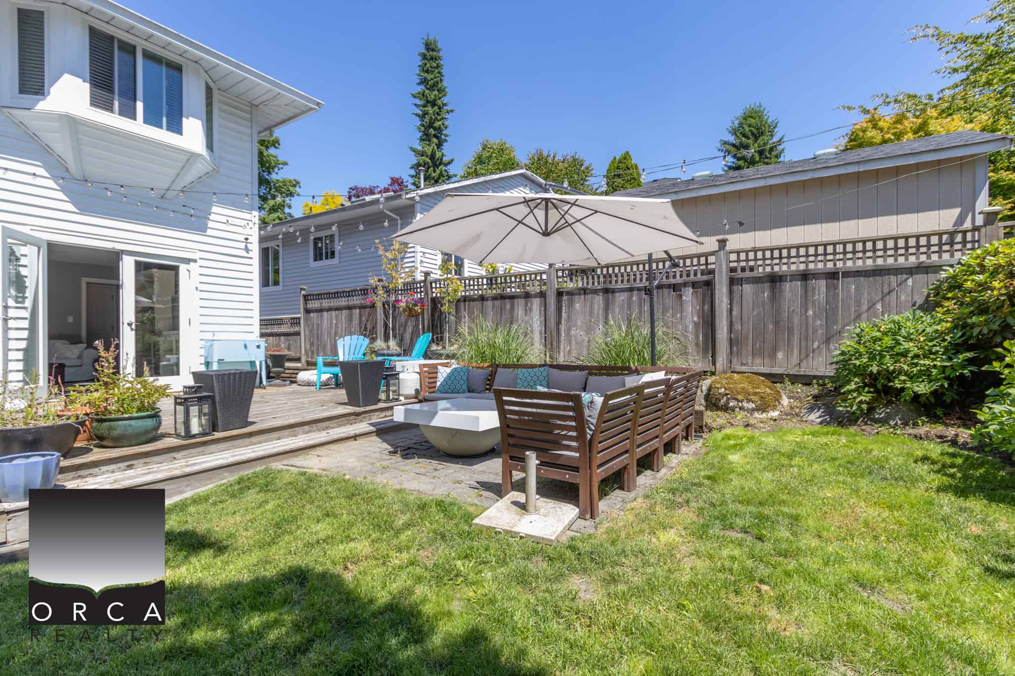 Spacious backyard with a wooden deck, outdoor seating, and greenery, providing an inviting outdoor living space for relaxation and entertaining in Vancouver’s vibrant real estate market.