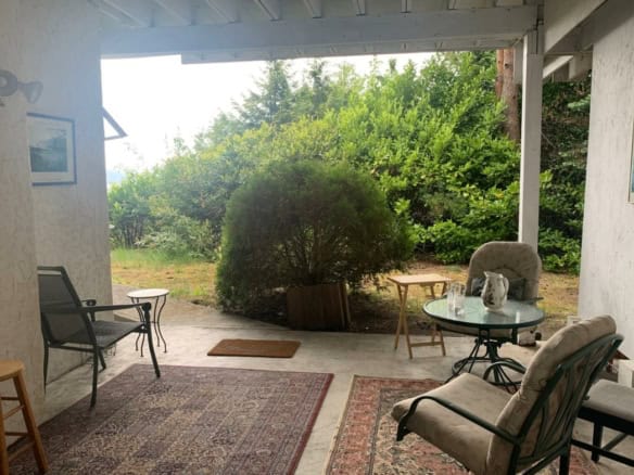 Cozy indoor and outdoor living space with view of lush greenery, perfect for relaxing or entertaining in Canadian home courtesy of Orca Realty Inc.