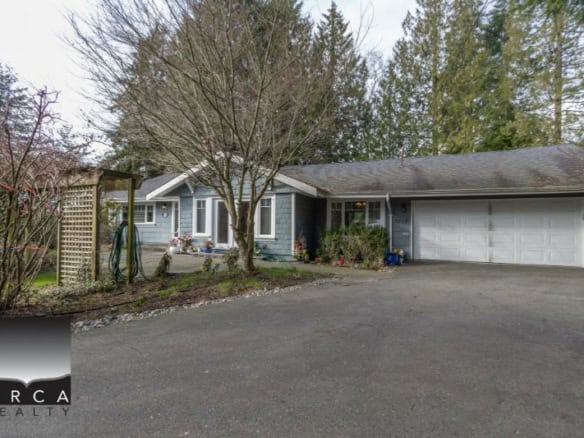 Modern family home in a quiet neighbourhood with a spacious driveway, well-maintained yard, and lush greenery, available through Orca Realty Inc., your trusted real estate partner in BC.