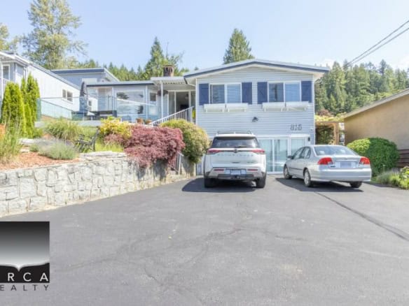 Modern waterfront home with stunning views in BC, featuring a spacious driveway, lush landscaping, and luxurious interior living spaces for sale or rent.