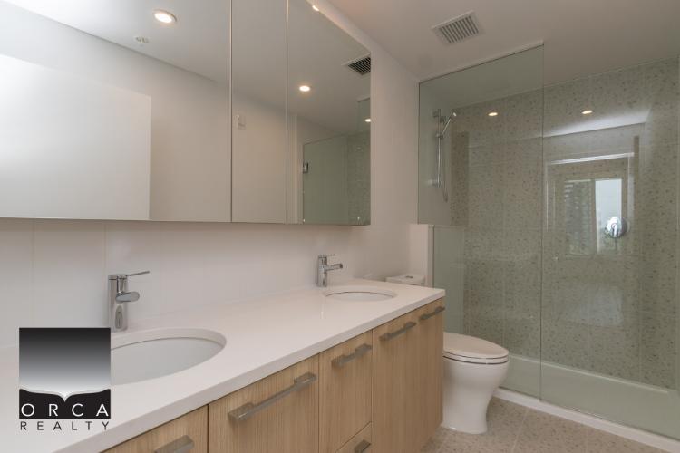 Bright modern bathroom with double vanity, large mirror, and walk-in glass shower in a contemporary condo near Vancouver. Perfect for real estate listings and property showcase.