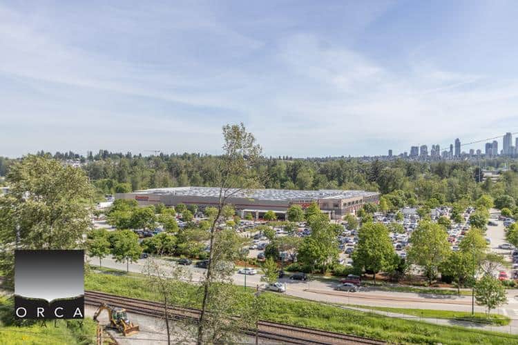 Orca Realty Inc. office building surrounded by lush greenery and parking lot, with Vancouver skyline in the background, showcasing prime commercial real estate opportunities in British Columbia.