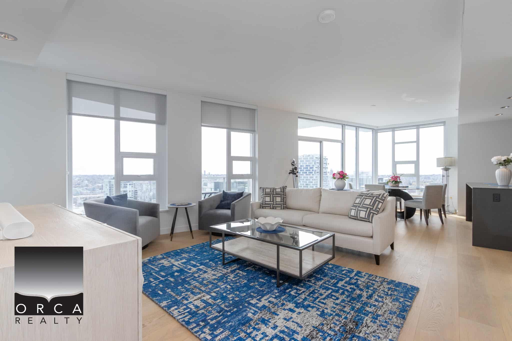 Modern luxury condo living room with panoramic city views in Vancouver, BC, featuring contemporary furniture, large windows, and stylish decor.