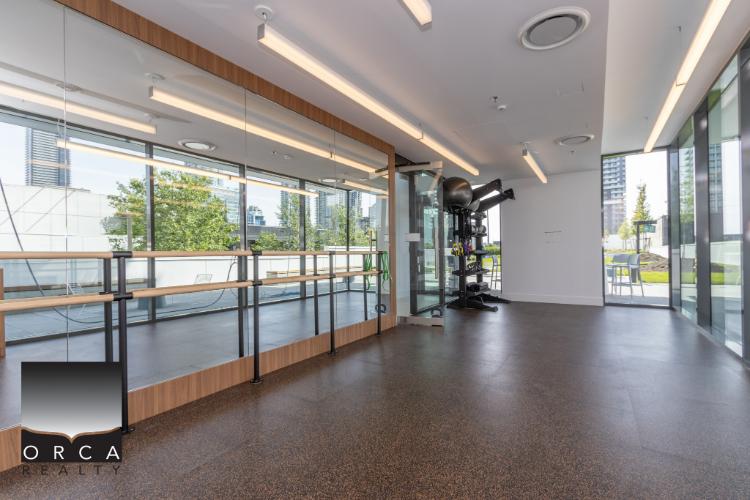Bright, modern fitness studio at Orca Realty Inc. offering spacious workout area with large windows, natural light, and professional equipment—ideal for health-conscious clients and real estate showcases.