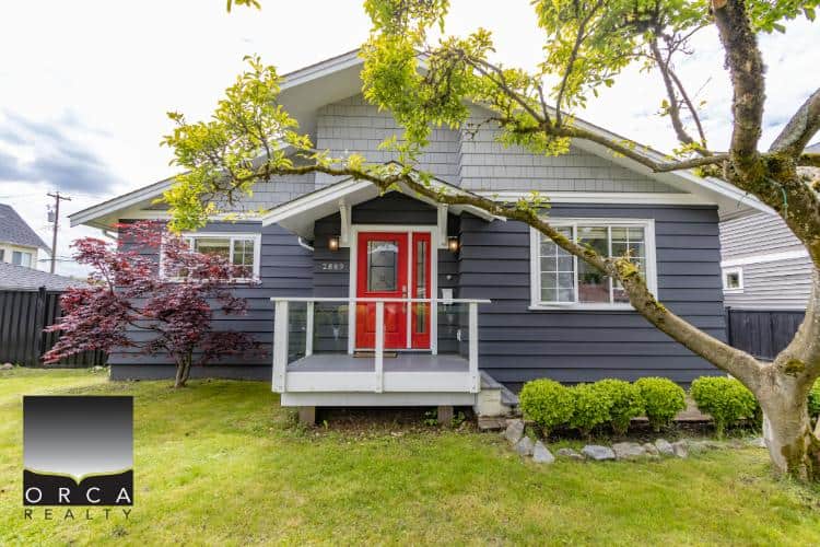 Charming modern house with a vibrant red front door, surrounded by lush greenery and mature trees, showcasing prime real estate listings by Orca Realty Inc. in Ontario.