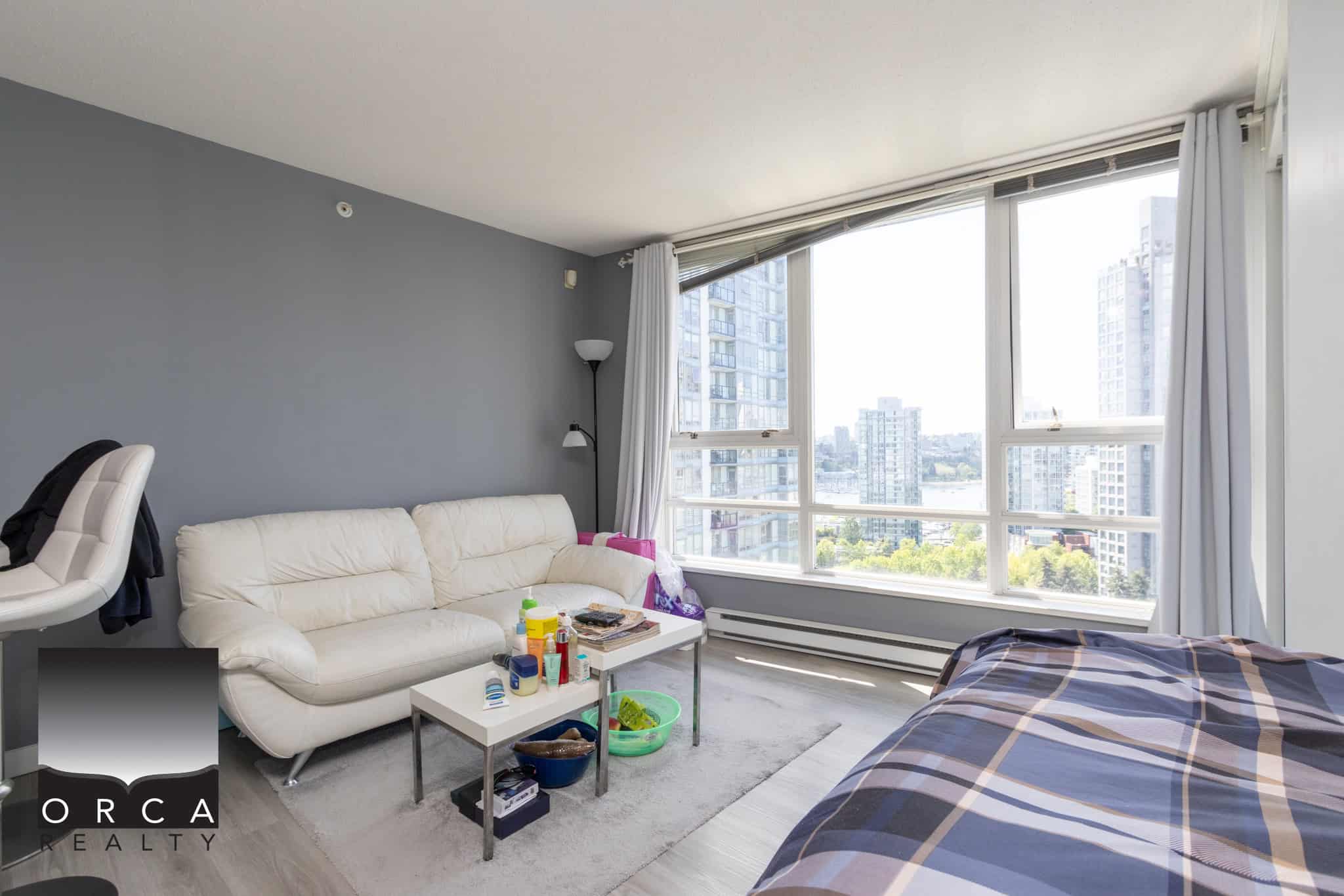 Bright living room with large windows overlooking downtown Vancouver, modern decor, and cozy furniture, ideal for urban condos and real estate in Vancouver, BC.