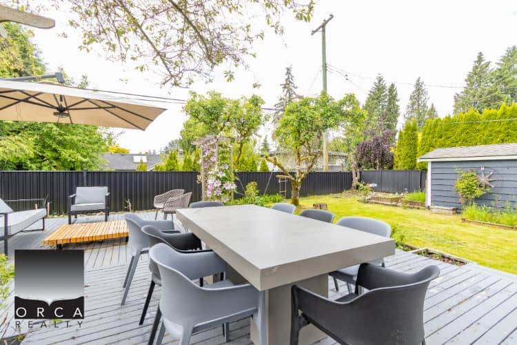 Modern outdoor patio dining area with table and chairs surrounded by lush garden and trees in Vancouver BC.