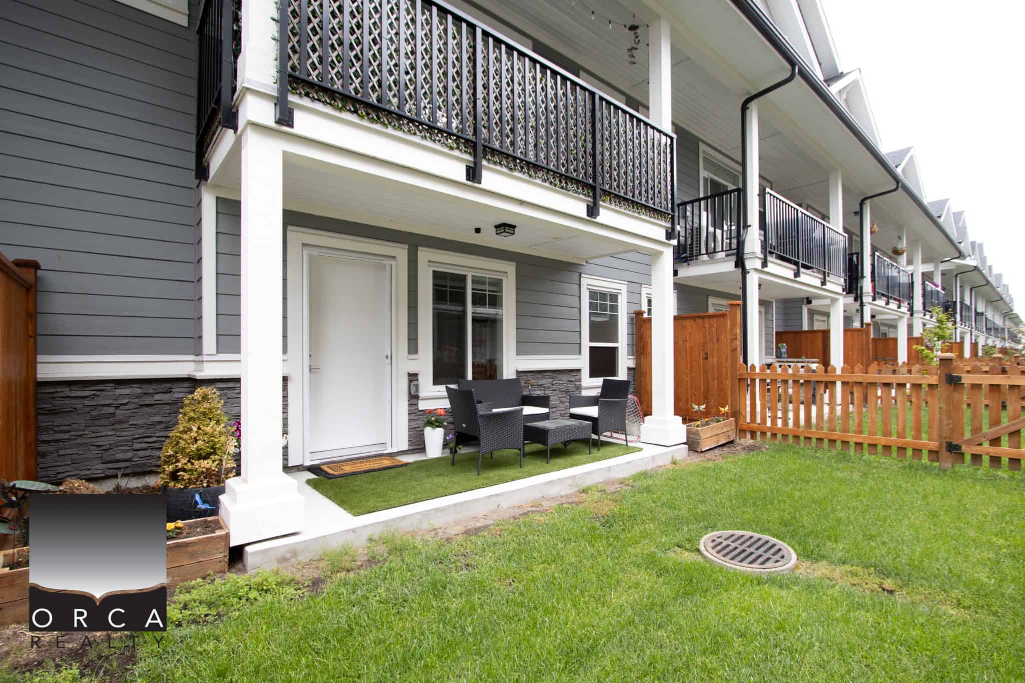 14 Cozy patio yard of a modern townhouse with outdoor seating and landscaped lawn, part of a quiet residential community with multi-story condos, promoting comfort and outdoor living in Vancouver.