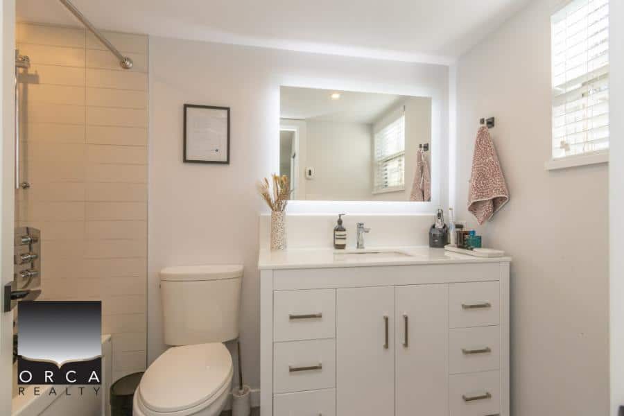 Modern bathroom with white vanity, large mirror, and natural light, showcasing high-quality real estate features. Perfect for homebuyers seeking elegant, updated interiors.