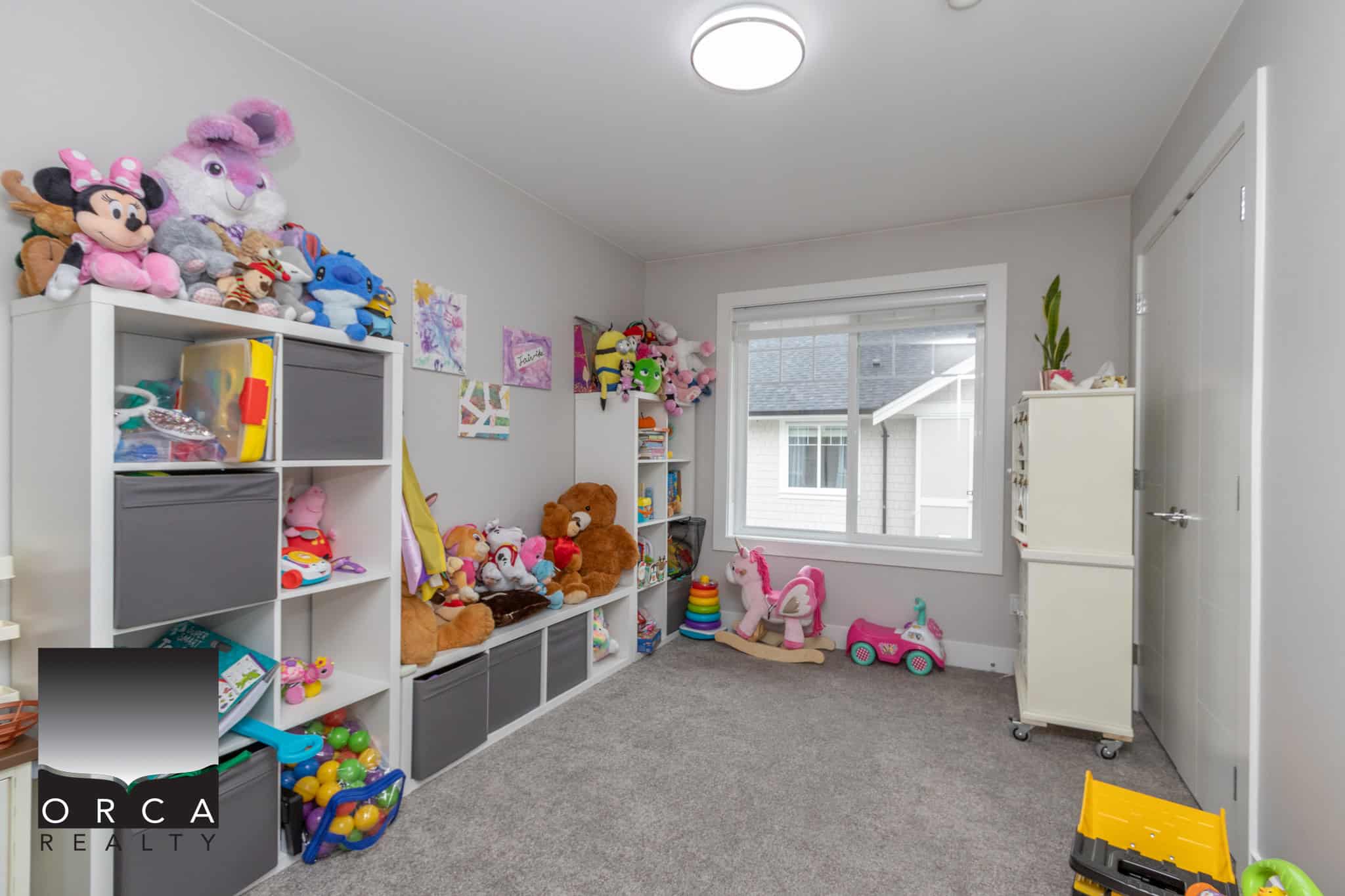 19 Colorful children's bedroom with plush toys and natural light from a large window, modern interior design, and organized storage solutions. Perfect for families seeking a welcoming, kid-friendly home in BC.