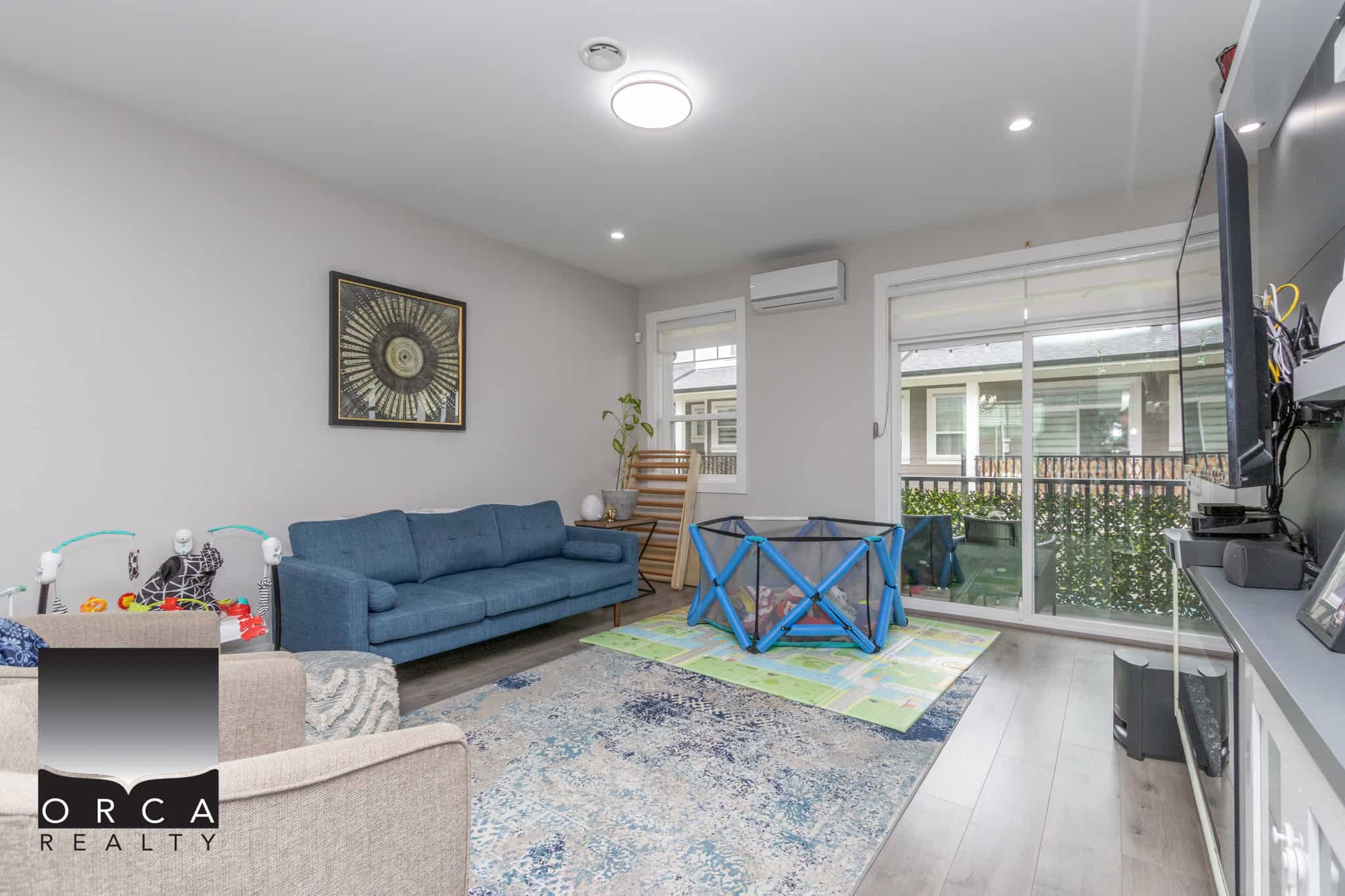 2 Bright living room with modern decor, large windows, and sliding glass door leading to the backyard, perfect for family gatherings and relaxation, featuring hardwood floors and cozy seating.