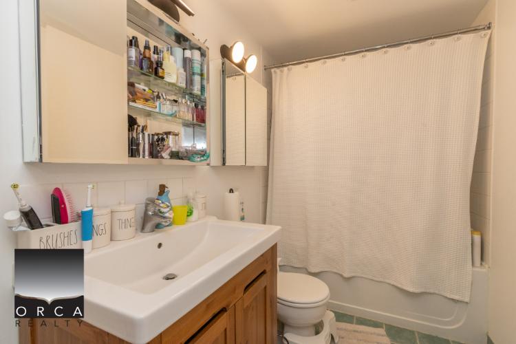 Mirror cabinet with toiletries and bathroom sink in a cozy, well-maintained Vancouver home bathroom.