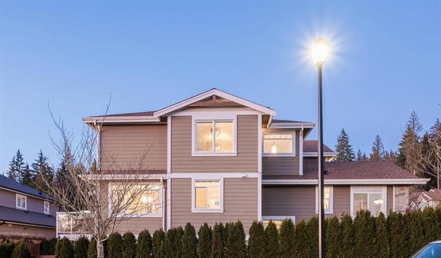 Modern residential house in a suburban neighbourhood under evening sky, illuminated by streetlights, showcasing contemporary architecture and well-maintained surroundings in British Columbia Canada.