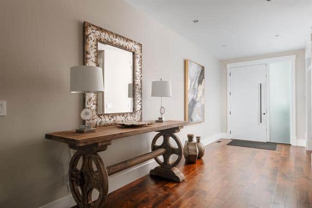 Stylish modern entryway with wooden console table, decorative lamps, and artwork, creating a welcoming and sophisticated home atmosphere.