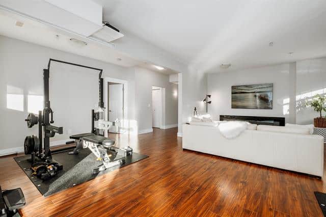Modern living room with gym area, hardwood flooring, and contemporary decor, showcasing spacious and stylish interior design for Vancouver real estate listings.