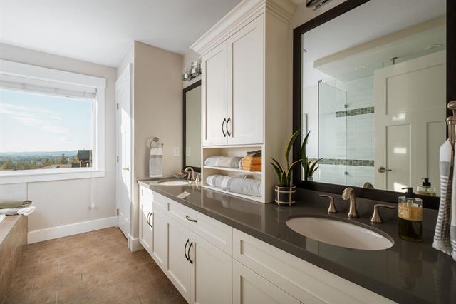 Modern bathroom with white cabinetry, large mirror, and glass shower enclosure in a bright, spacious home. Perfect for luxury real estate listings and showcasing Vancouver Island properties.